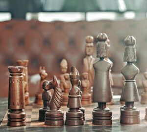 Wooden chess pieces arranged on a board, engaged in a chess match