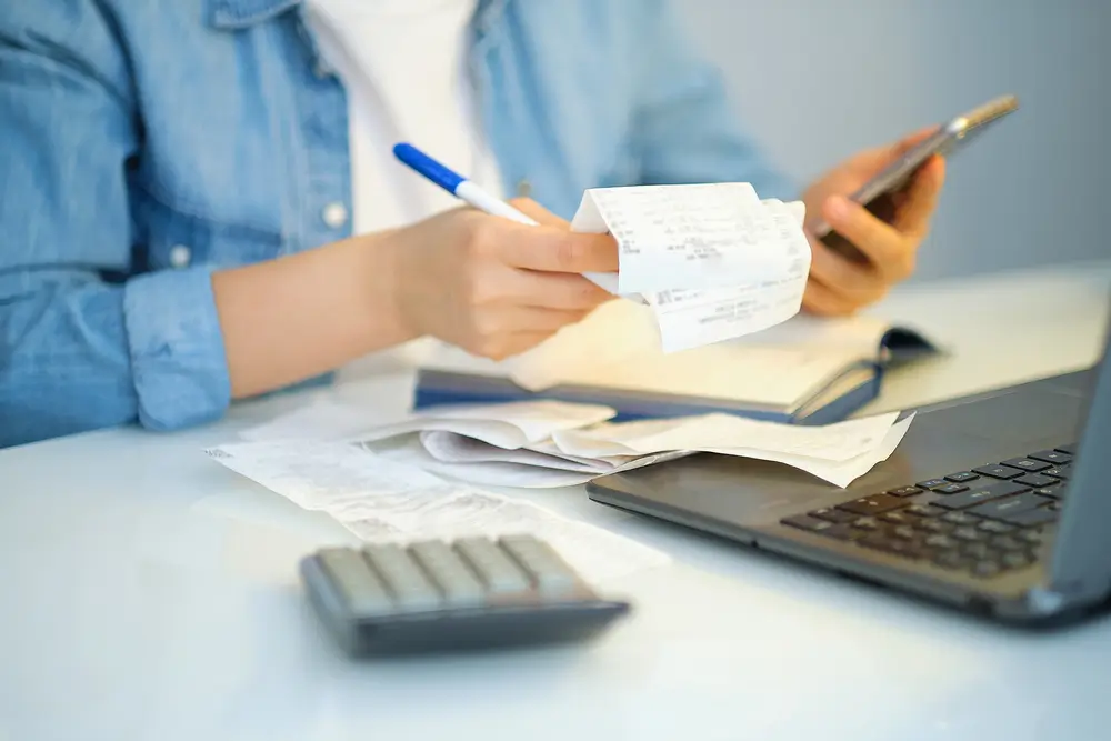 A person doing bookkeeping services while holding receipt and pen